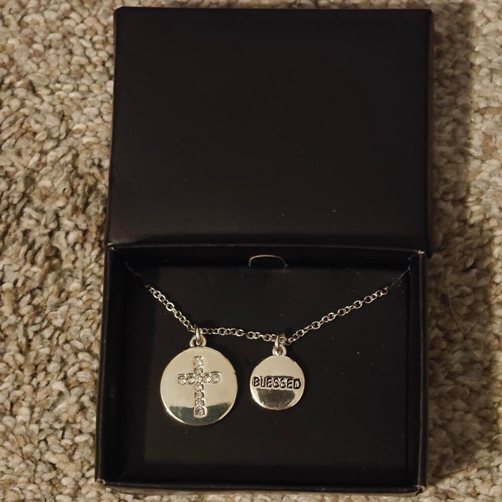 Silver necklace with two circular pendants, one with a cross and the other with
